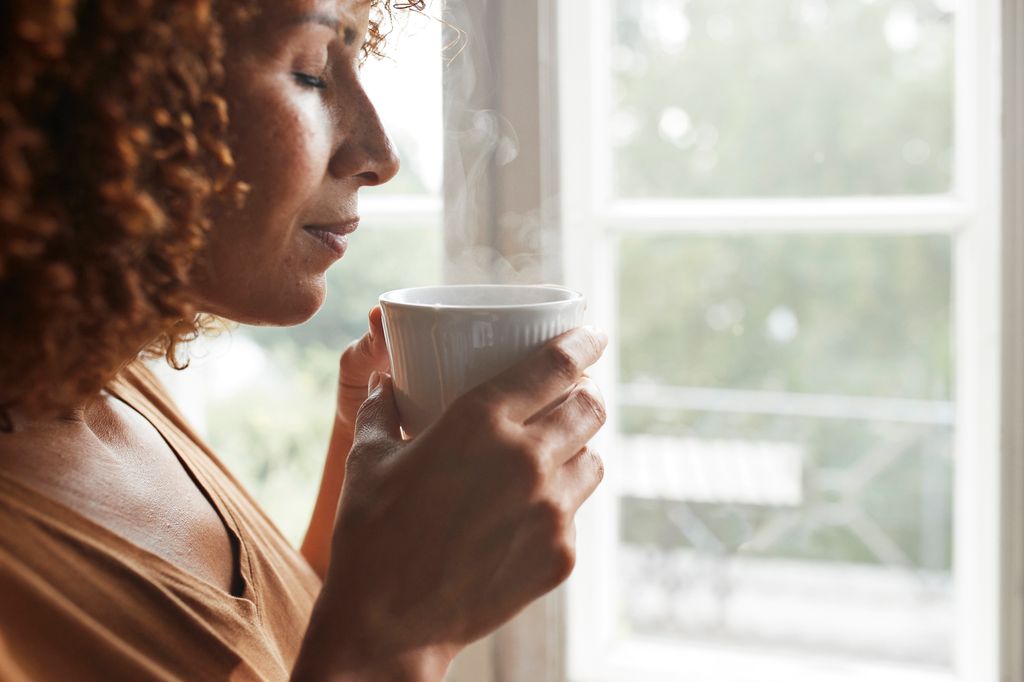 Mature woman smelling coffee at home