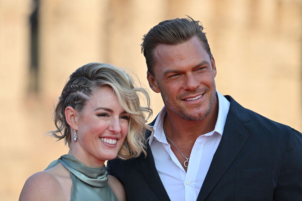 Alan Ritchson and his wife smiling dressed smartly