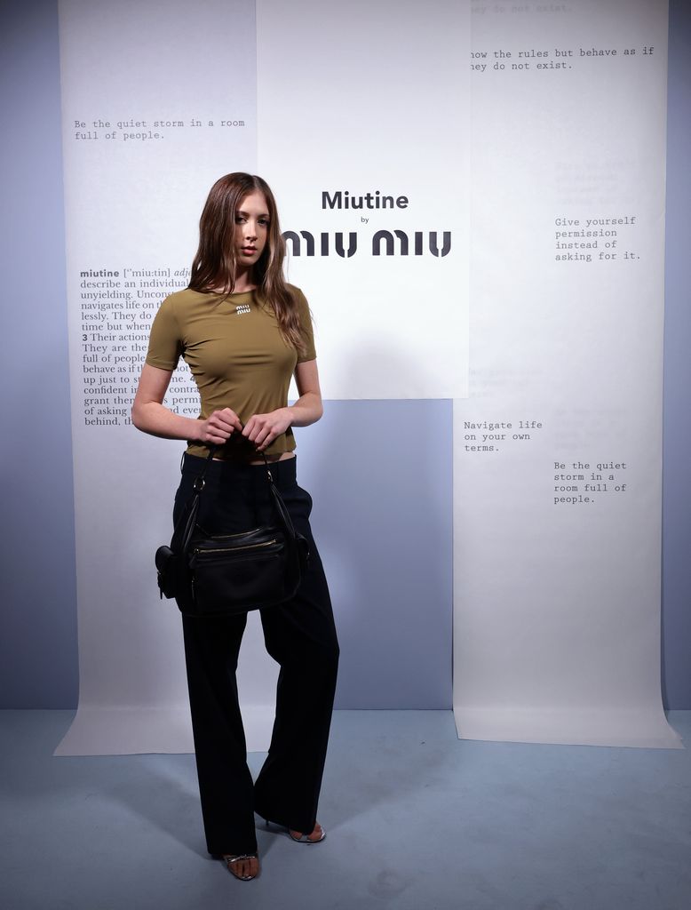 Sunday Rose at he Miutine Club event in green top and navy pants holding a leather miu miu bag