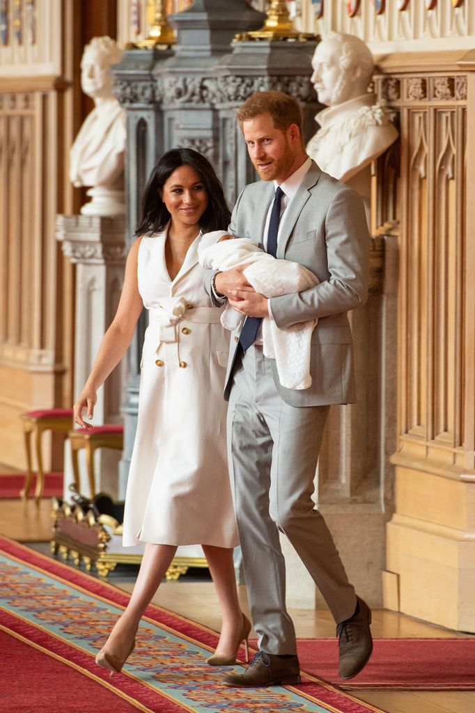 Prince Harry holding baby Archie with Meghan Markle walking next to them