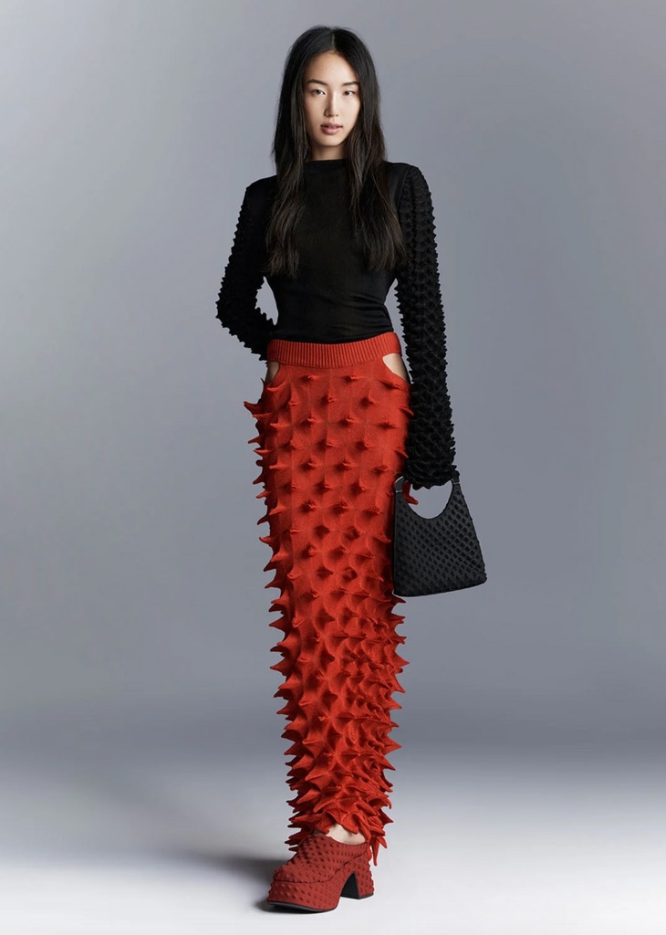 Charles & Keith x Chet Lo collaboration. Model wears a red maxi skirt, red platform shoes, a black longsleeve and black handbag