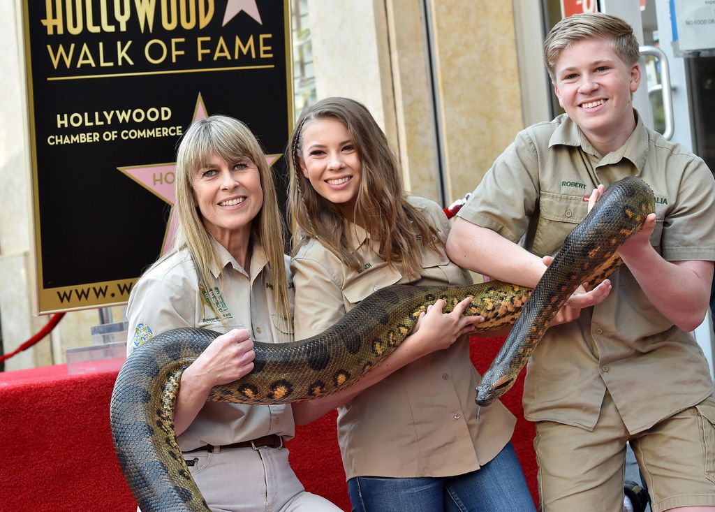 Bindi Irwin holds a snake as she joins her mum Terri and her brother Robert