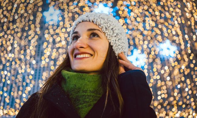 lone woman smiling serenely at the christmas lights above