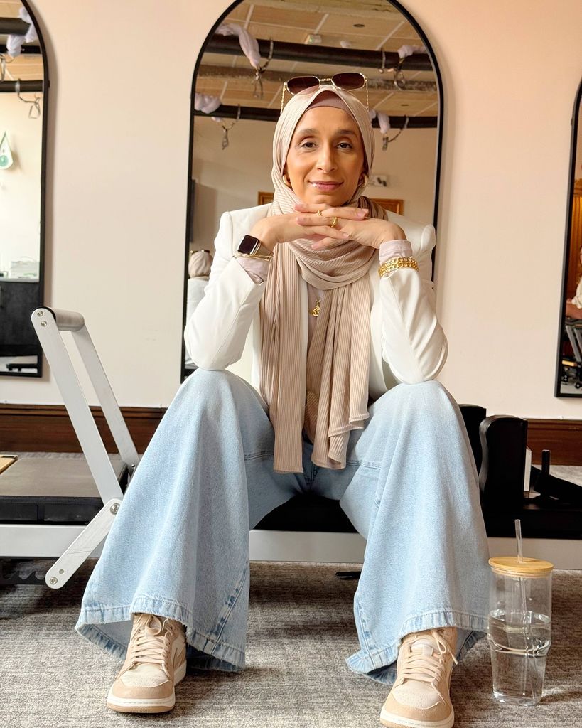 woman in head scarf sitting on reformer pilates bed 