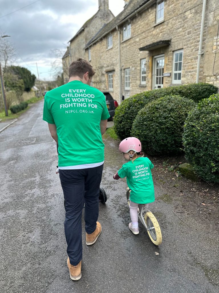 man wearing green NSPCC with girl riding bike