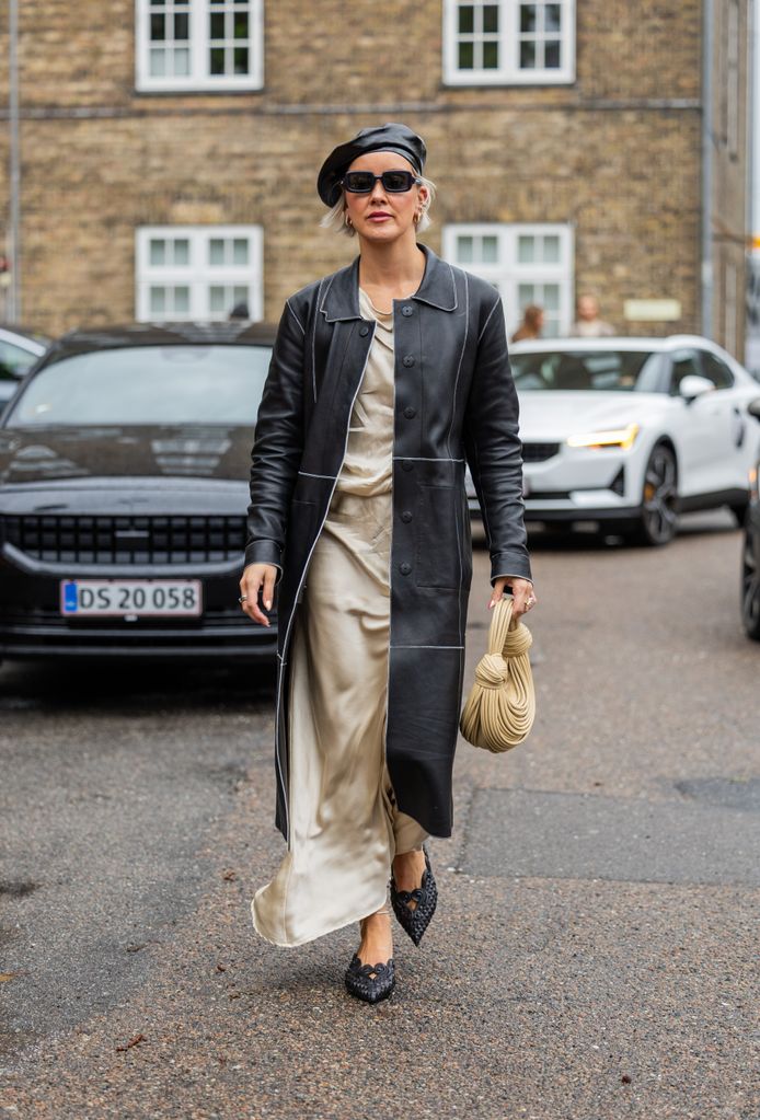 Tina Haase wears black belted coat, leather beret, Bottega Veneta beige bag, skirt, sunglasses outside 7 Days Active during the Copenhagen Fashion Week Spring/Summer 2024