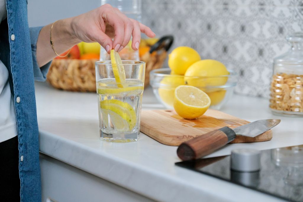 Femme mettant des tranches de citron dans l'eau froide