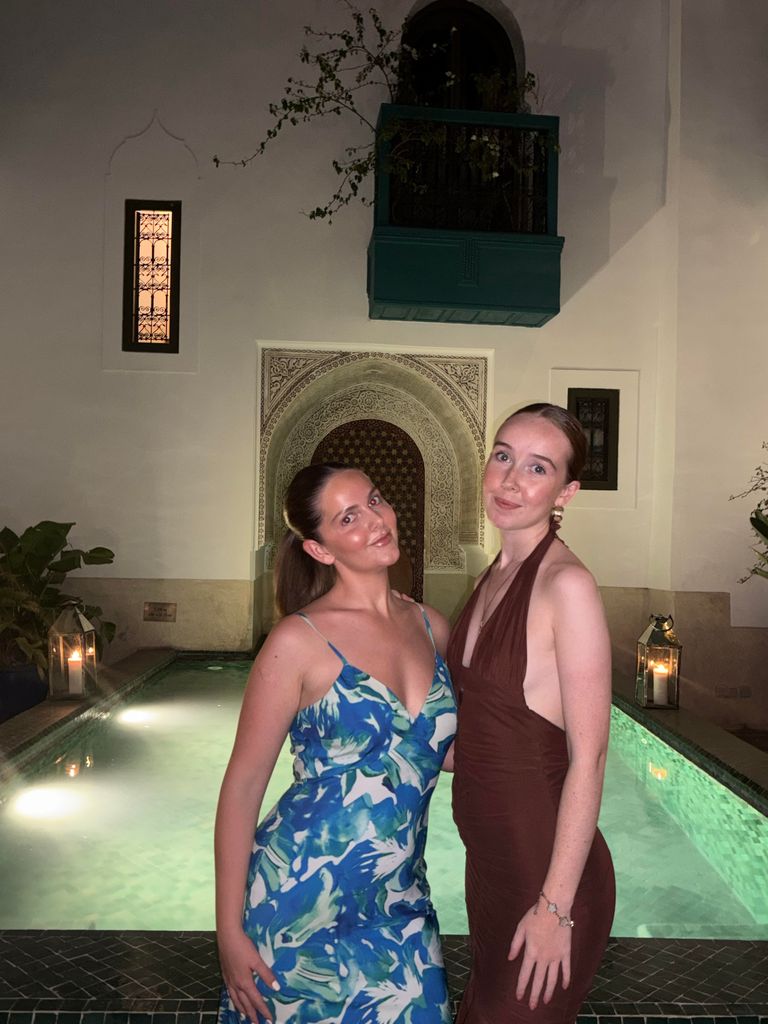 Two girls in dresses standing in front of an outdoor pool