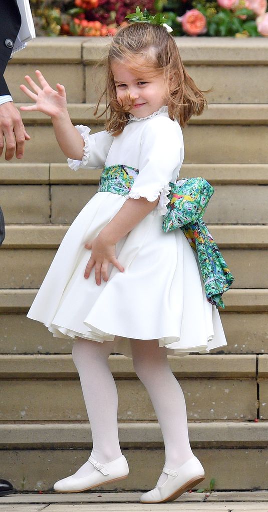 Princess Charlotte waves to crowds in a white flower girl dress