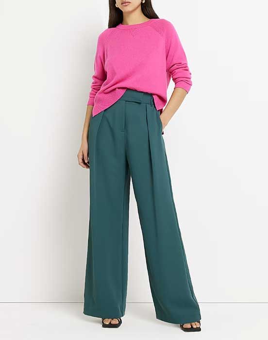 model wearing green wide legged trousers and pink top