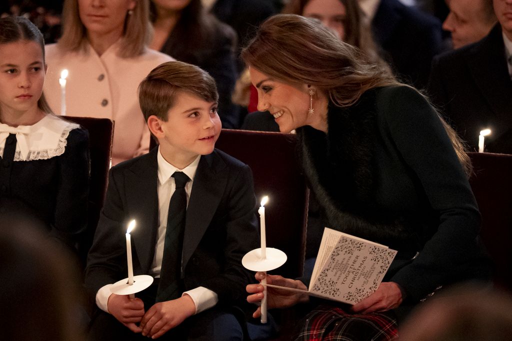 Prince Louis sitting with his mum, Kate Middleton; Princess Charlotte sits to their left