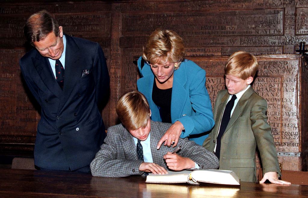 Prince William signing the Eton book with King Charles, Princess Diana and Prince Harry looking on