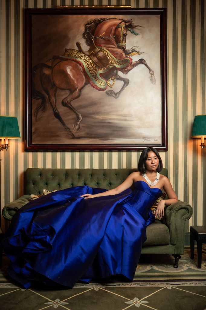 Jillian Chan posed on grand green chair in cobalt dress
