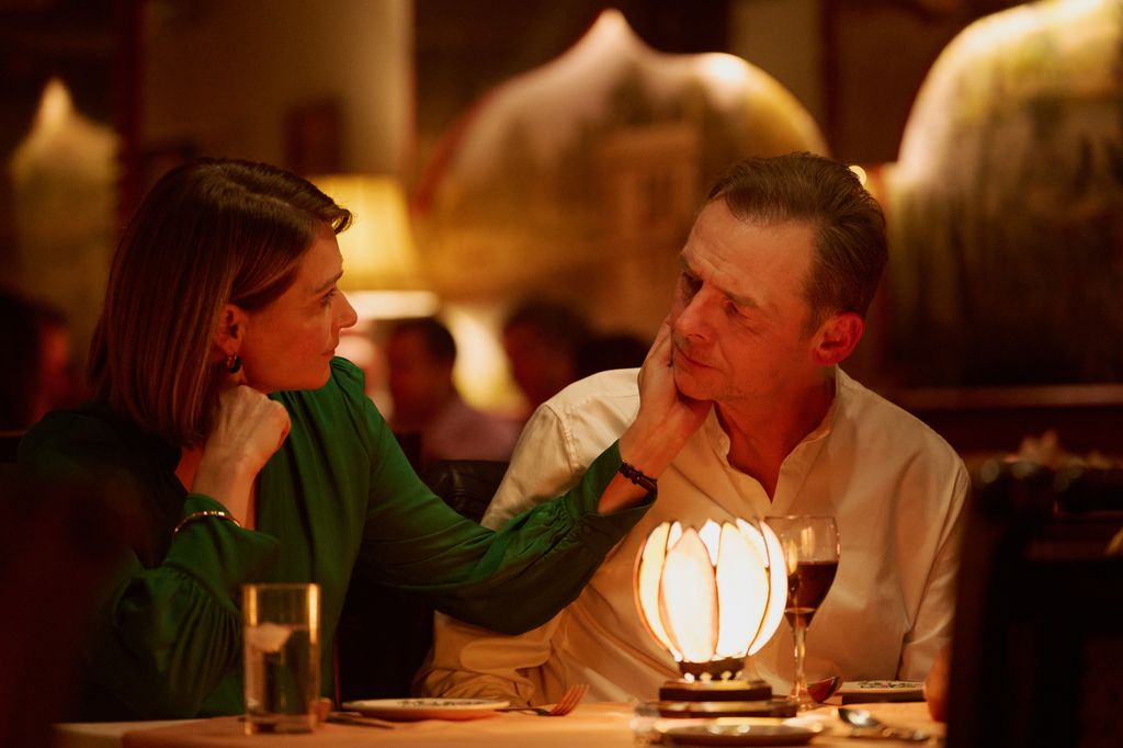 A woman holding a man's face whilst sitting in dimly lit restaurant