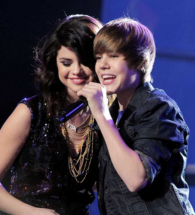 Selena and Justin leaning in to each other as they sing together on TV