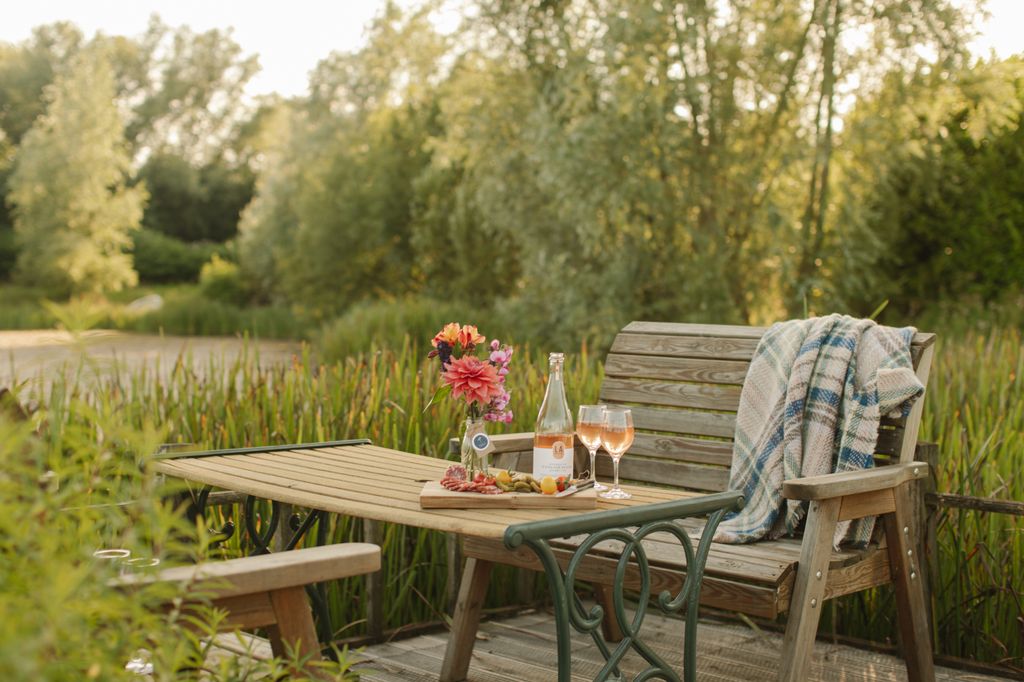 bench next to pond with table laid out with food and wine