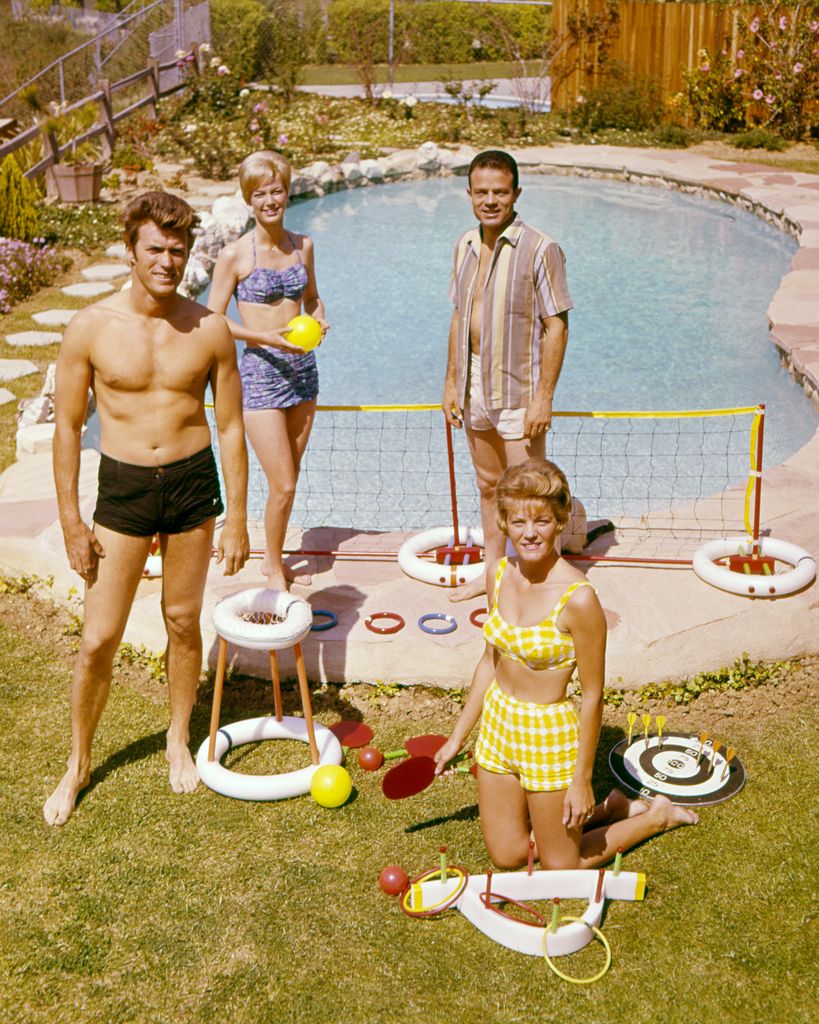 Clint Eastwood (left) with his wife, Maggie (foreground), and friends by a swimming pool, circa 1960