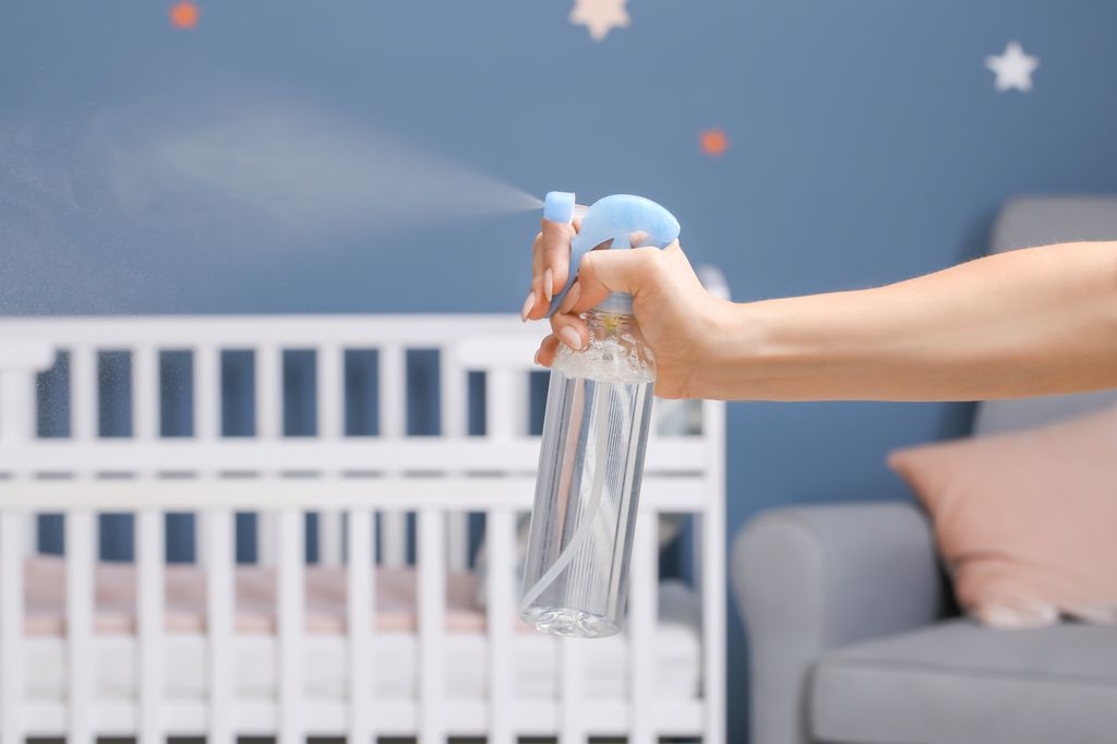 woman spraying air freshener in a baby's bedroom