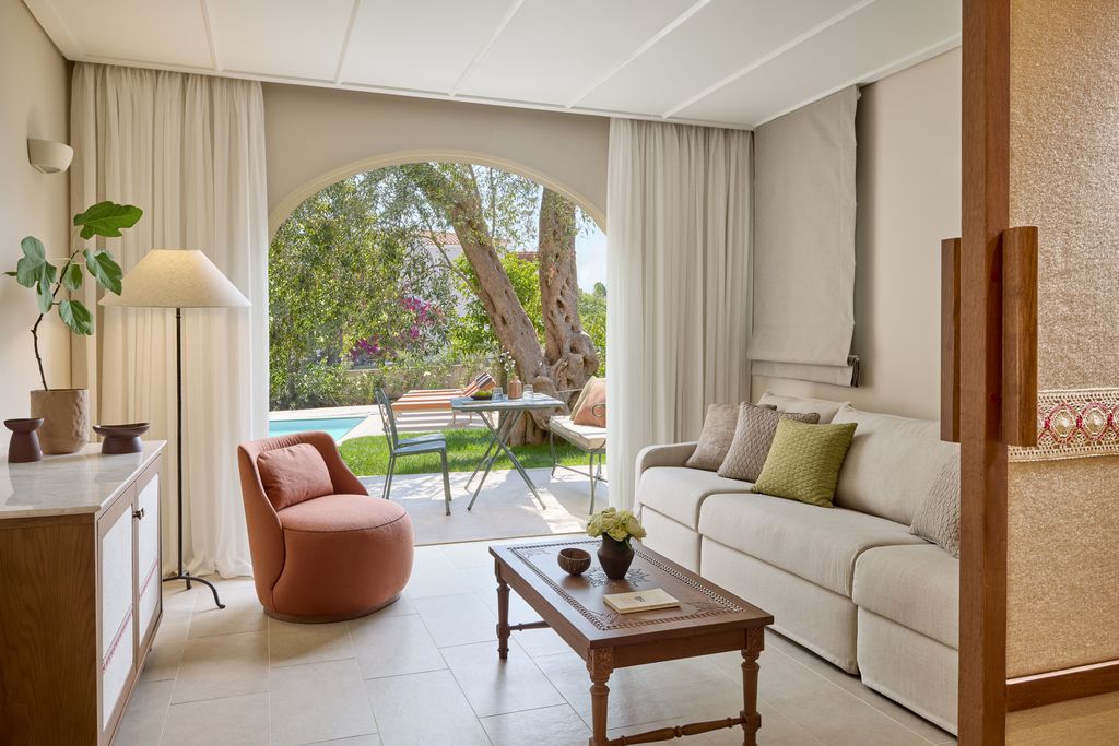 Hotel suite with table, sofa leading into a patio and pool area