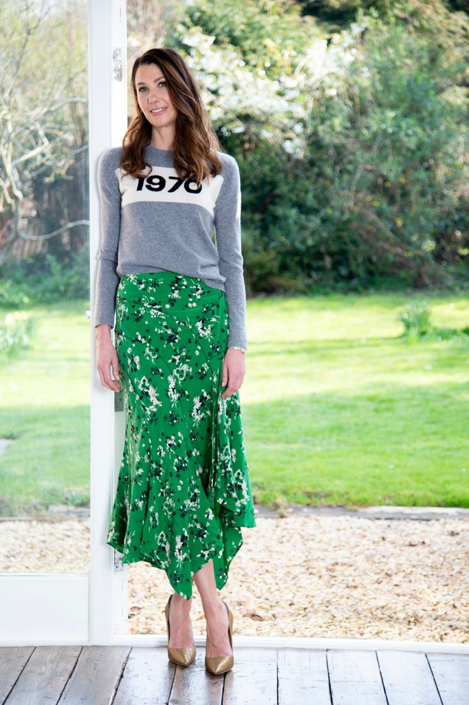 woman in grey top and green skirt posing outside