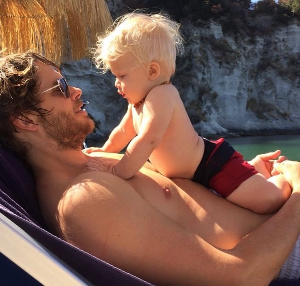 Eric Christian Olsen sits with his young son lying on her chest 