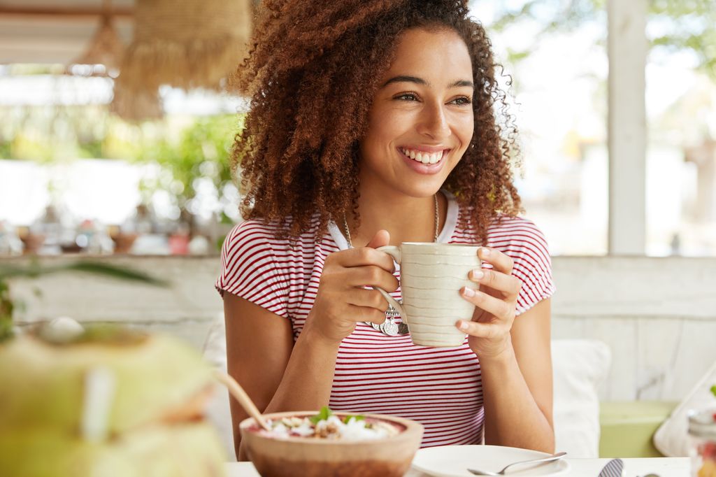 Young woman smiling white she eats breakfast