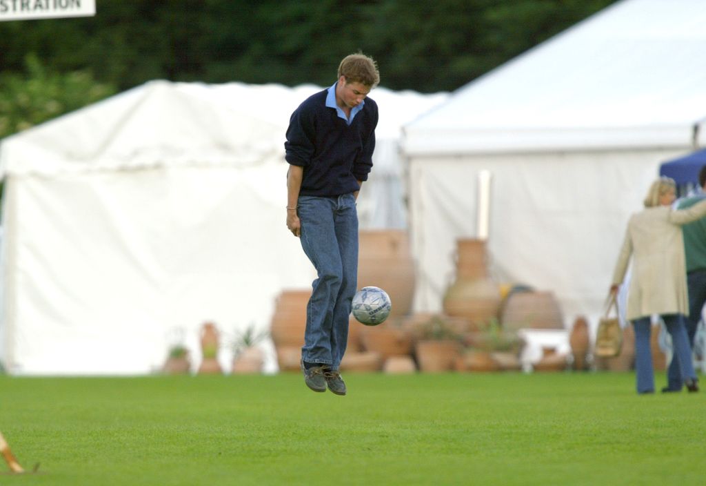 Prince William jumping up to kick a football