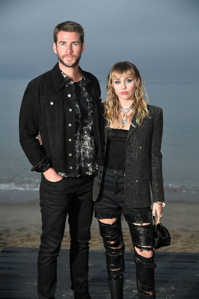 Liam Hemsworth in black denim and Miley Cyrus in gray blazer and ripped pants at the Saint Laurent Mens Spring Summer 20 Show Photo Call 