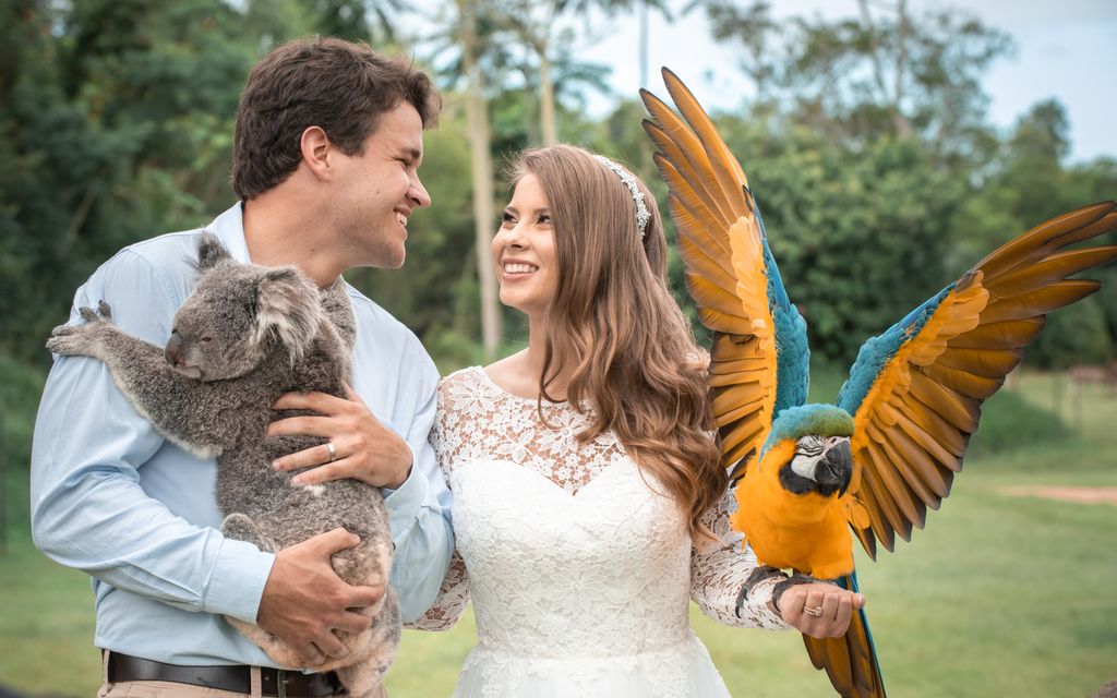 Bindi Irwin looks adoringly at Chandler, who is carrying a koala, on their wedding day