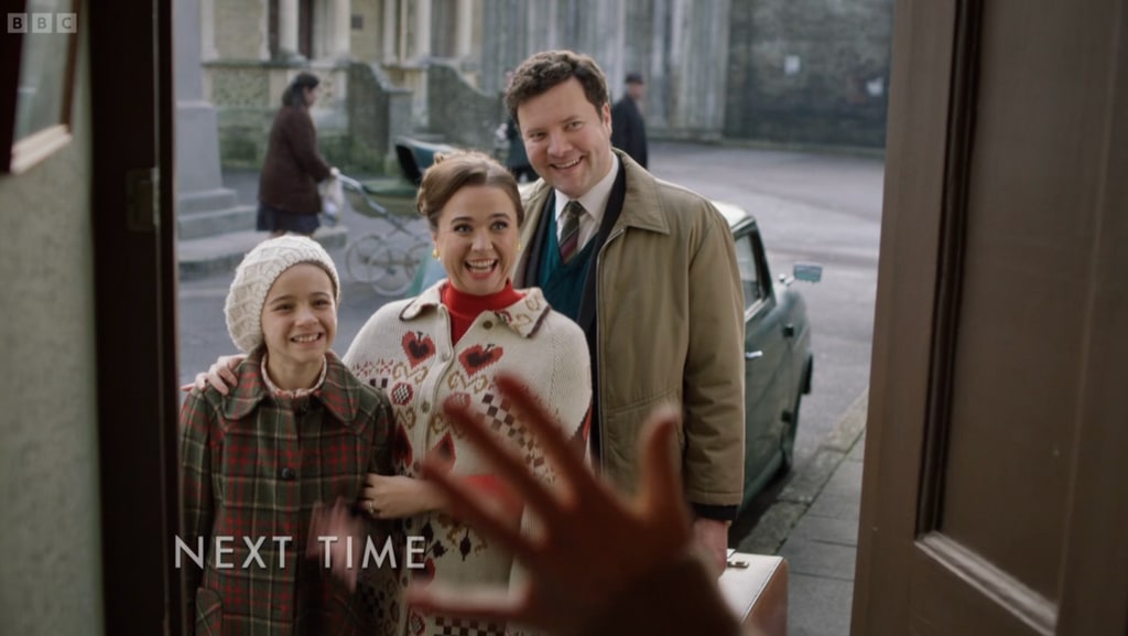 Three people in period clothing standing outside front door