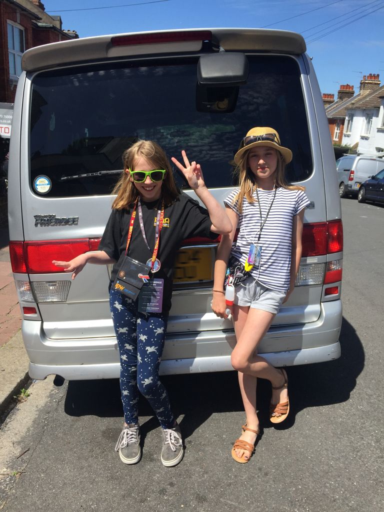 Two kids posing for a photo in front of a car