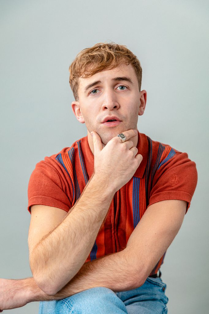 young male actor in red shirt with hand on chin