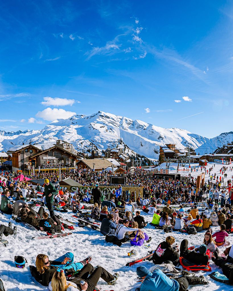 Snowboxx festival-goers sitting on the snow and dancing