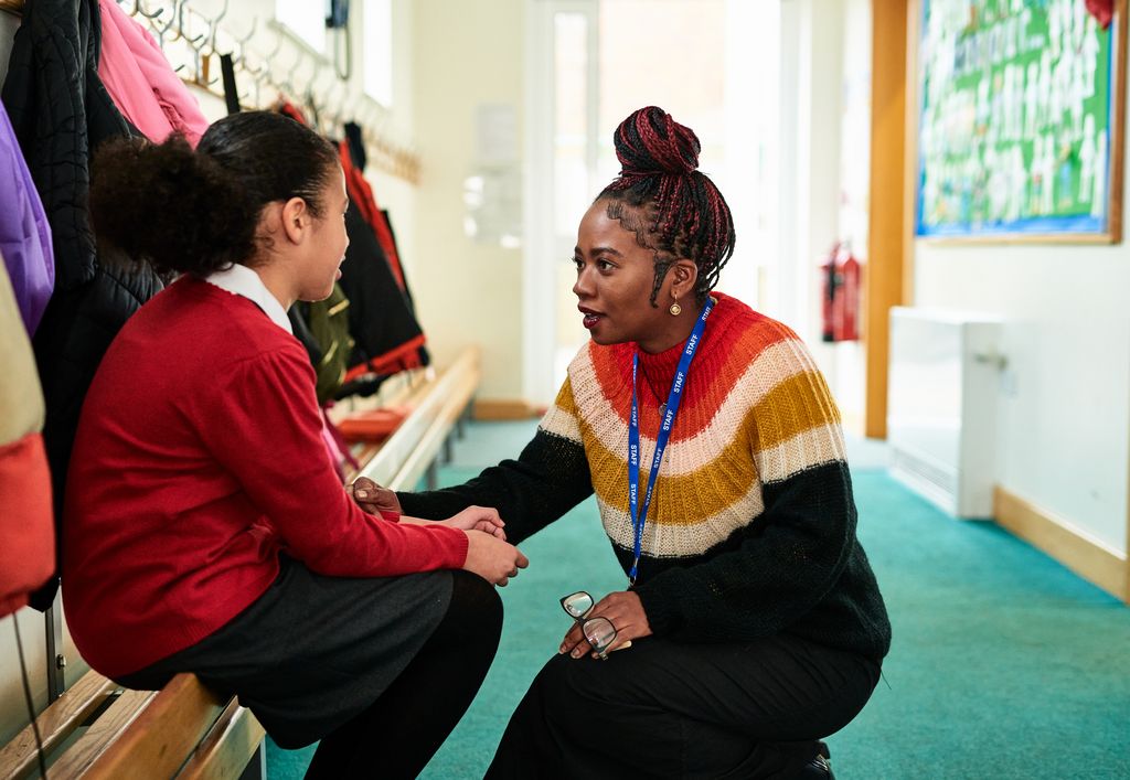 school girl sitting on bench talking to teacher