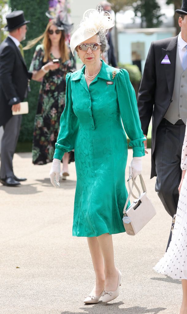 Princess Anne wears a green dress with white gloves and a cream handbag