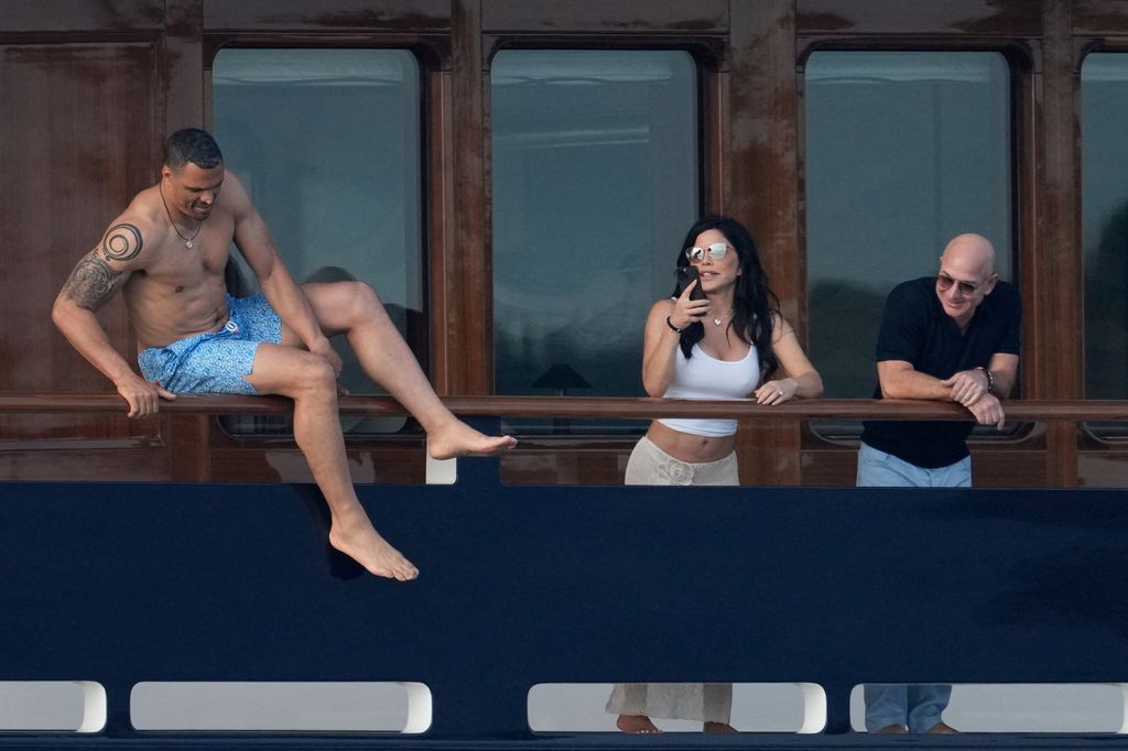 Lauren Sanchez and Jeff Bezos are watching as a shirtless man jumps off the yacht