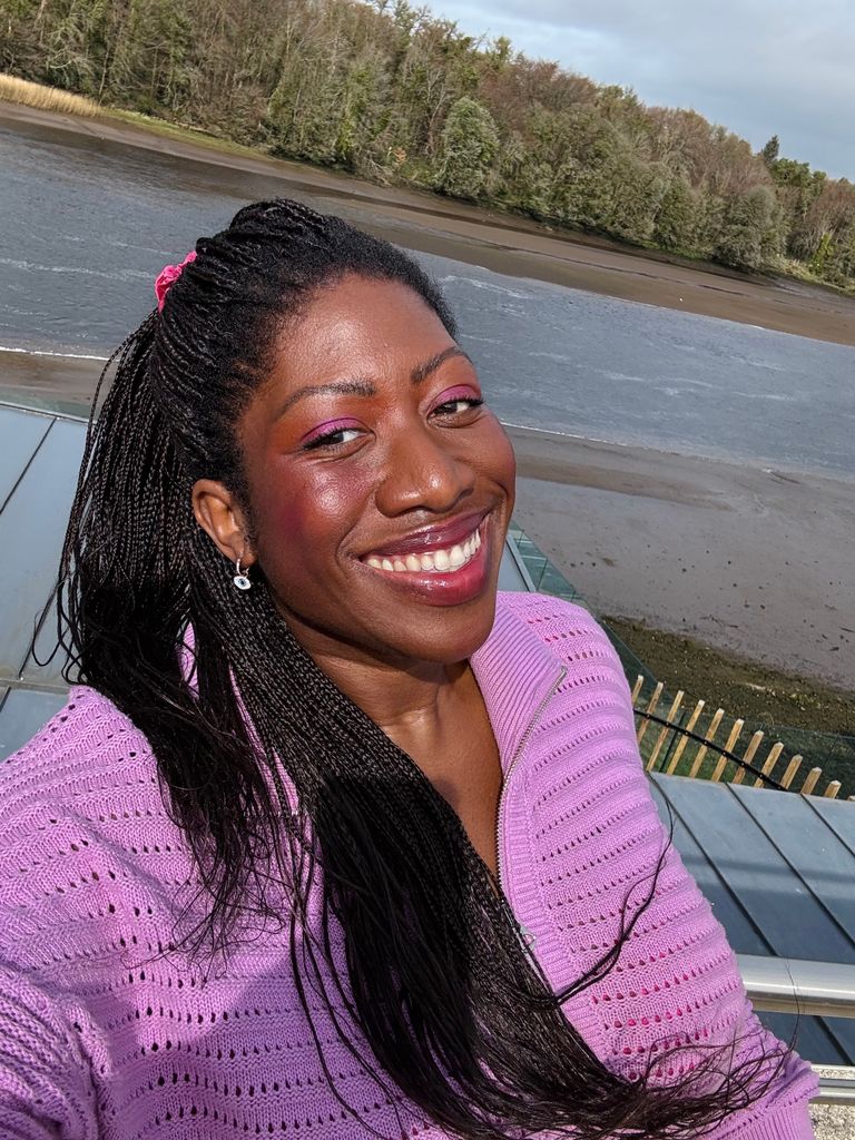 Woman smiling for a selfie on a lake in a purple jumper