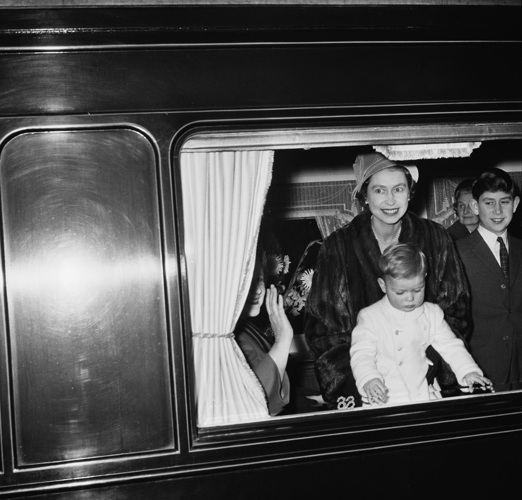 British Royals Queen Elizabeth The Queen Mother (partially obscured behind curtain, 1900-2002), her daughter Queen Elizabeth II with her sons, Prince Andrew and Prince Charles, on the train to spend Christmas at the Sandringham Estate, Norfolk, England, 21st December 1961 