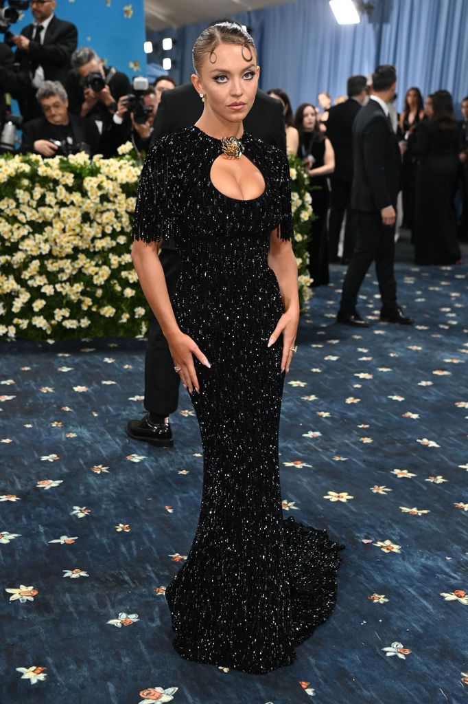 Sydney Sweeney wears a black glittering full length dress with cut out detail