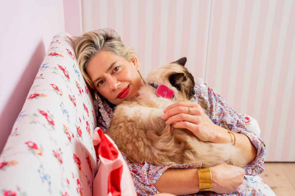 A woman lies on a sofa with a pet cat