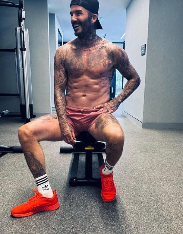 A shirtless David Beckham on a workout bench