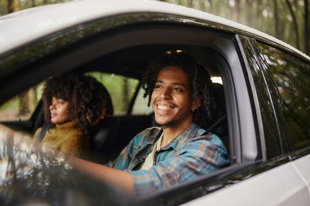 Man driving a car while going on a road trip with his girlfriend