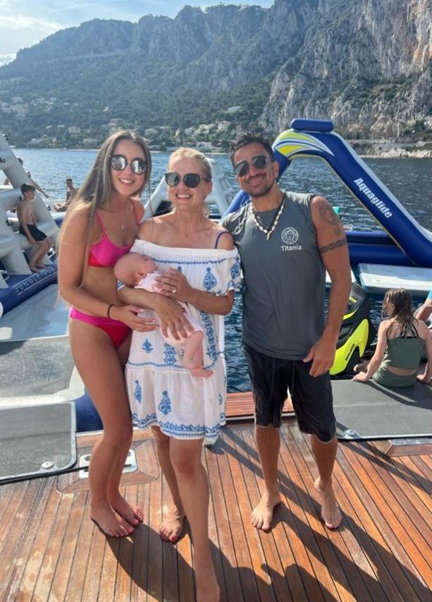 Emily Andre in pink bikini stood with Peter Andre and a woman holding a baby