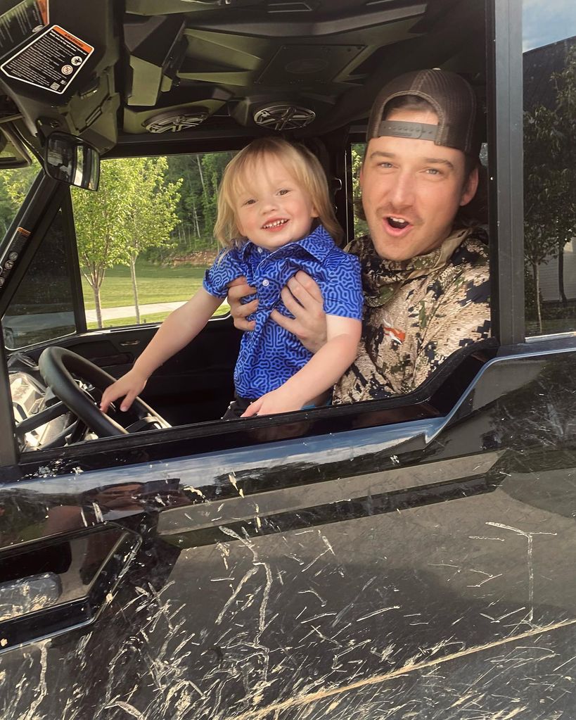 Man holding his baby while they sit in a truck