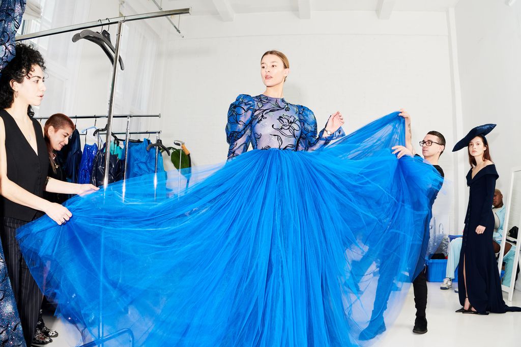Fashion designer Christian Siriano working with model wearing blue dress