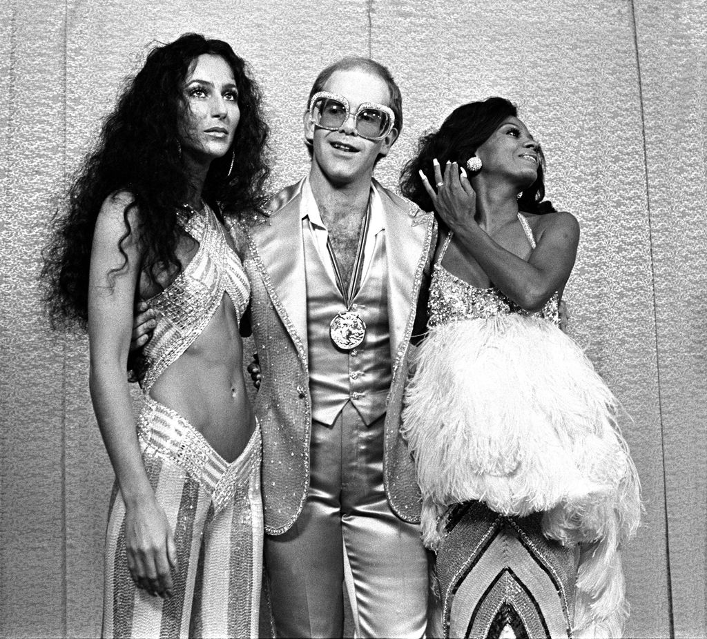 Cher, Elton John and Diana Ross dressed in glamorous outfits 