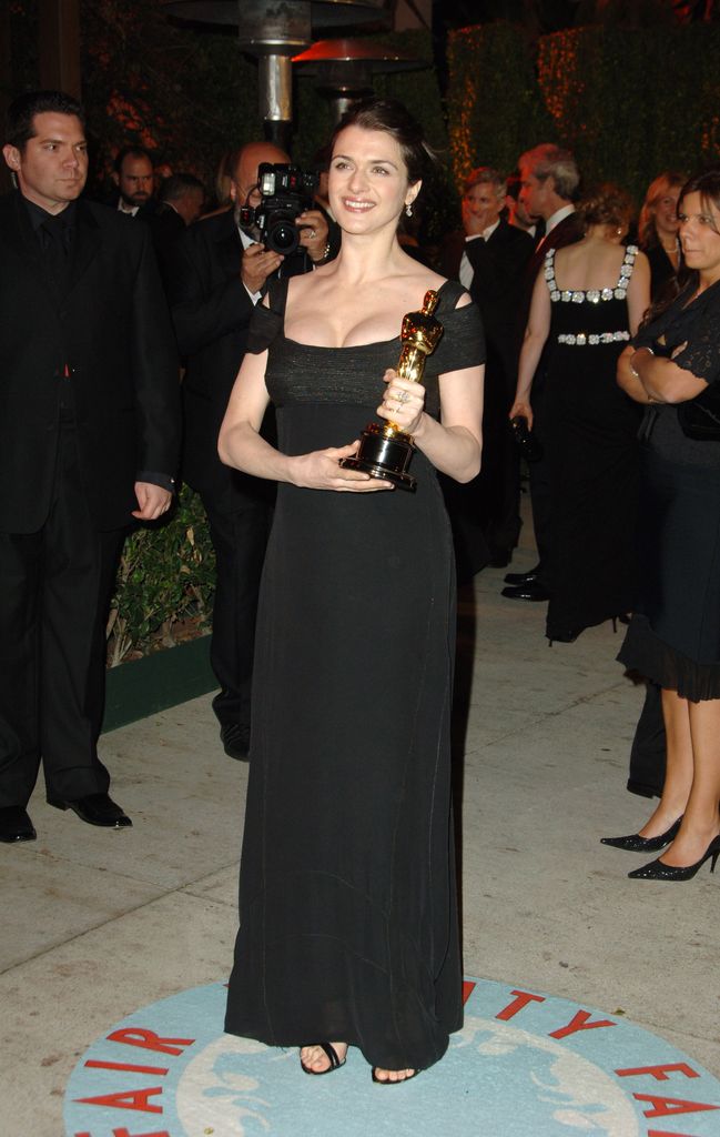 Rachel pregnant with Henry in black dress holding OScar