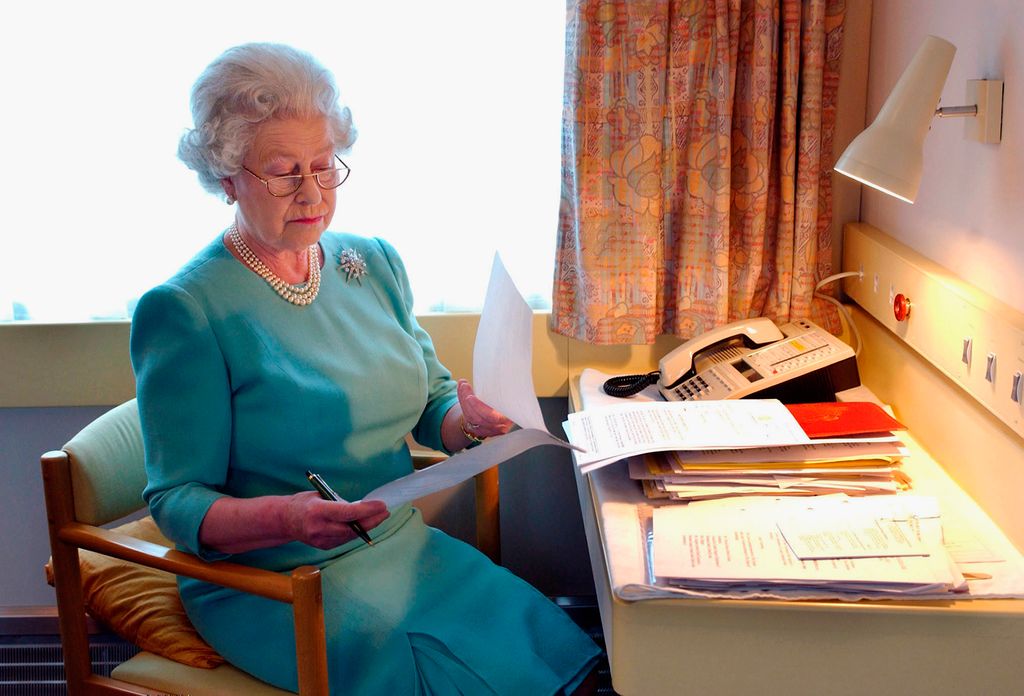 Queen Elizabeth II works at her desk on the Royal Train in May of 2002