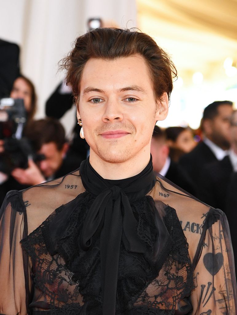 Harry Styles at the 2019 Met Gala wearing a sheer Gucci blouse and a single pearl earring.