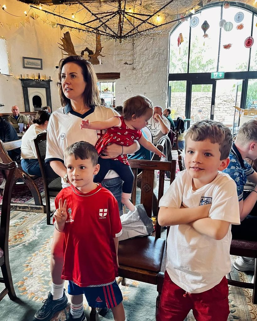 mum holding baby standing next to two young sons